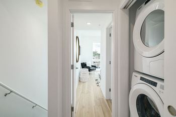 A white washing machine is in the foreground of a hallway.